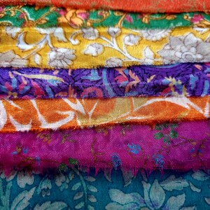 May include: A stack of colorful fabric scraps with floral patterns in shades of green, yellow, purple, orange, pink, and blue.