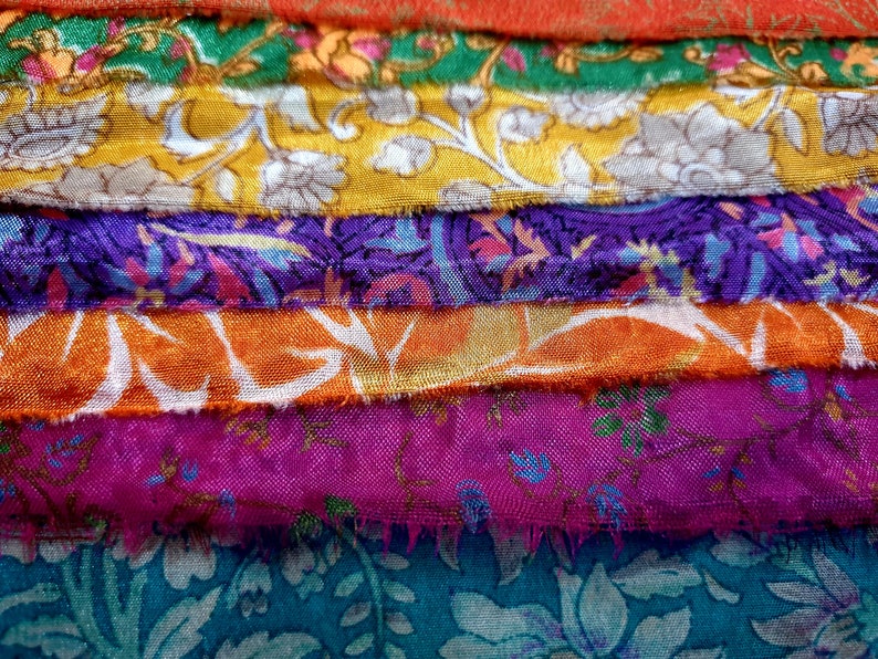 May include: A stack of colorful fabric scraps with floral patterns in shades of green, yellow, purple, orange, pink, and blue.