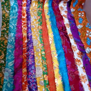 May include: A collection of colorful fabric strips with floral patterns. The strips are arranged vertically and are of varying widths. The fabric is a mix of silk and cotton.