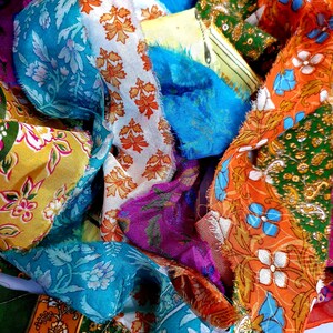 May include: A collection of colorful fabric scraps in various patterns, including floral, paisley, and geometric designs. The fabric is arranged in a loose pile, with the edges of the scraps visible.