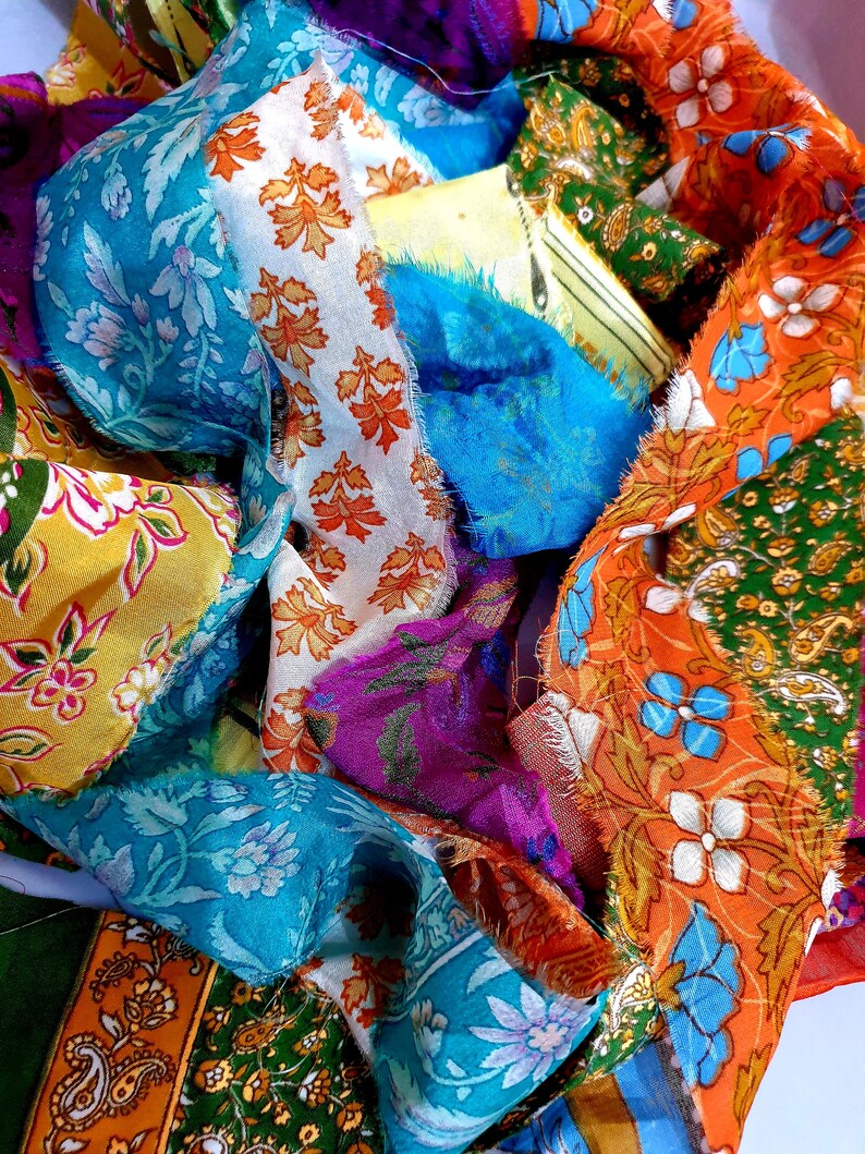 May include: A collection of colorful fabric scraps in various patterns, including floral, paisley, and geometric designs. The fabric is arranged in a loose pile, with the edges of the scraps visible.