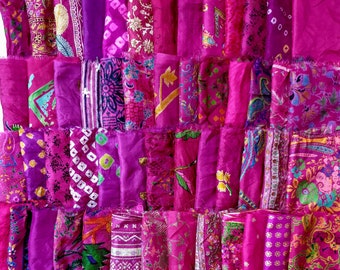 May include: A patchwork quilt made from various pieces of pink and purple silk fabric with floral and geometric patterns.
