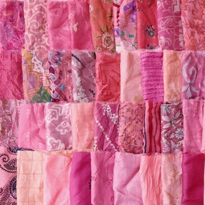 May include: A collection of pink fabric scraps with various patterns and textures. The fabric is arranged in a grid pattern, creating a patchwork effect.