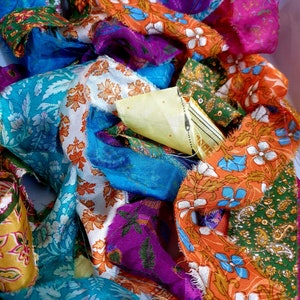 May include: A pile of colorful fabric scraps with floral patterns in shades of orange, blue, green, purple, and white.