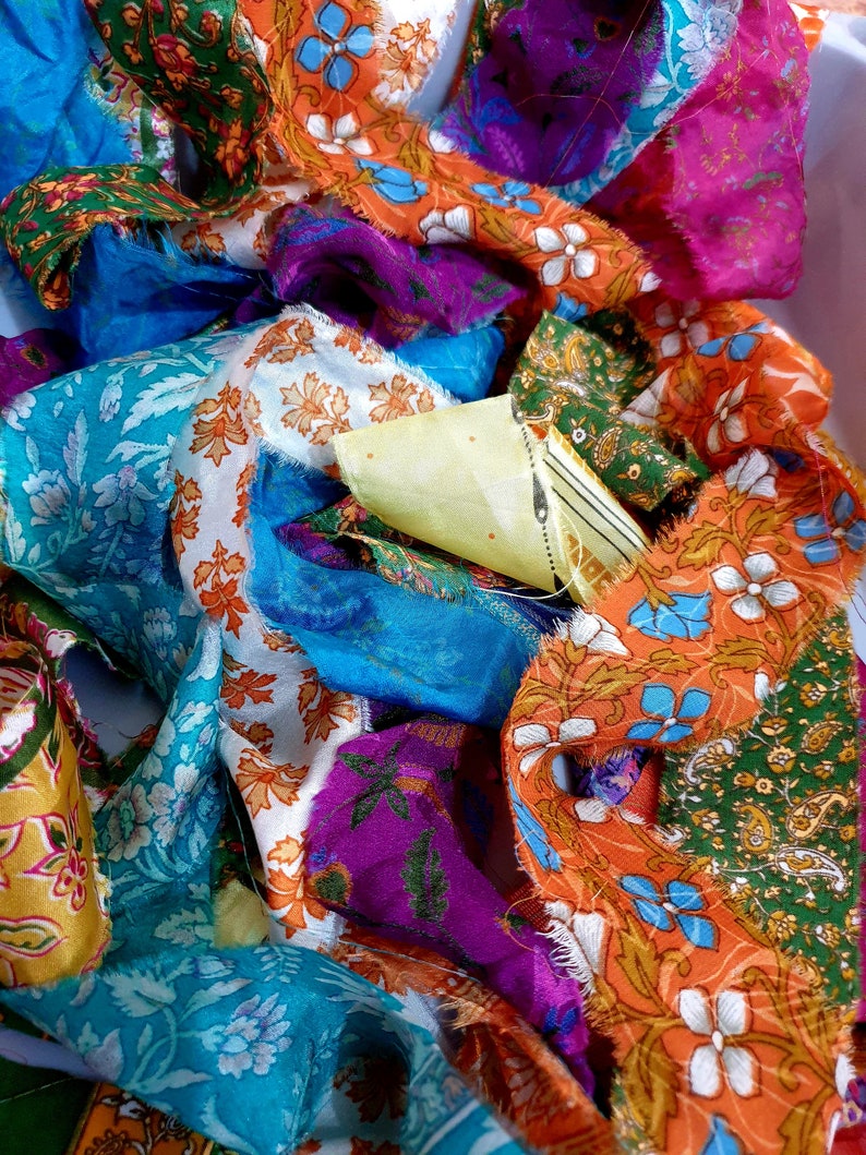 May include: A pile of colorful fabric scraps with floral patterns in shades of orange, blue, green, purple, and white.