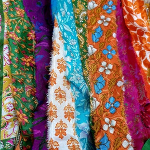 May include: A close-up of a colorful fabric scrap with various floral patterns in shades of green, blue, orange, purple, and white.