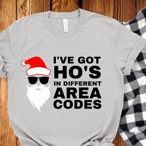 May include: A gray t-shirt with a Santa Claus graphic and the text "I've got Ho's in different area codes".