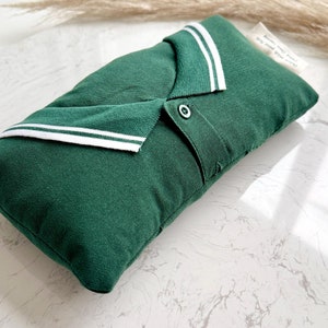 Könnte beinhalten: Ein grünes Kissen in Form eines Poloshirts mit weißen Streifen am Kragen. Das Kissen hat einen Knopf auf der Vorderseite.