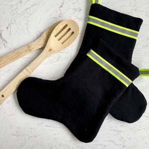 May include: Black stocking with a yellow reflective stripe. The stocking is made of a soft, stretchy fabric and is perfect for adding a festive touch to your holiday decor.