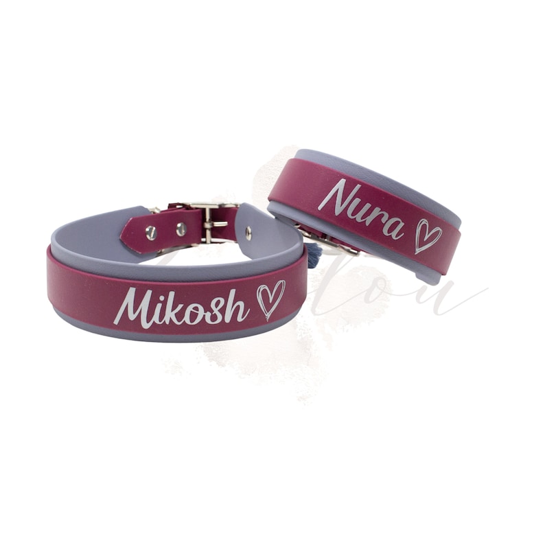 Puede incluir: Dos pulseras de cuero personalizadas, burdeos y grises. Una pulsera tiene grabado el nombre "Mikosh", la otra "Nura", cada uno seguido de un coraz&oacute;n. Las pulseras tienen una hebilla met&aacute;lica.