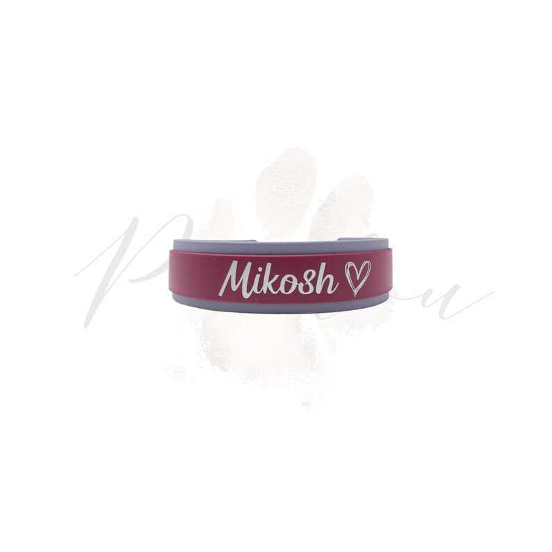 Puede incluir: Un collar para mascotas de color granate y gris con el nombre "Mikosh" y un s&iacute;mbolo de coraz&oacute;n grabado en blanco. El collar tiene forma rectangular con bordes redondeados. El fondo es blanco con una huella de pata.