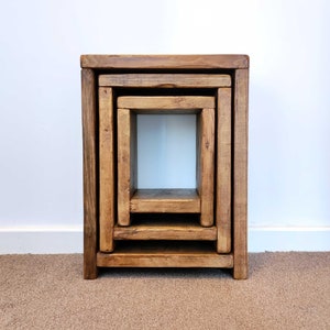 May include: Set of four wooden nesting tables with a natural brown finish. The tables are stacked on top of each other, creating a unique and stylish design.