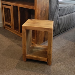Peut inclure: Une petite table d'appoint en bois avec une seule étagère. La table est faite de bois de récupération et a une finition rustique et naturelle.