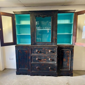 May include: A black antique cabinet with glass doors and three drawers. The cabinet has a distressed finish and is painted turquoise inside.