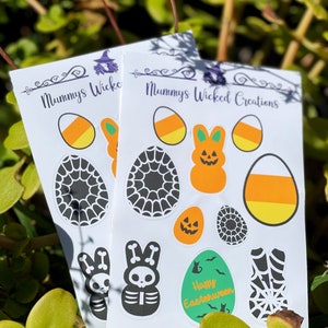 May include: Two white sticker sheets featuring Halloween and Easter-themed designs. The stickers include candy corn, spiderwebs, jack-o'-lanterns, skeleton bunnies, and the text "Happy Easterween". The brand name "Mummy's Wicked Creations" is also visible.