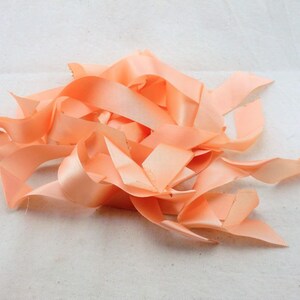 Peut inclure: Un tas de chutes de ruban de satin de couleur pêche. Le ruban est doux et soyeux, et les chutes sont de différentes longueurs.