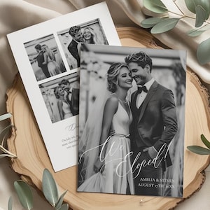 May include: Two black and white wedding announcement cards with photos of a couple, one card reads "We Eloped!" with the couple's names and date. The cards are on a wooden slice with greenery and a cream-colored fabric background.