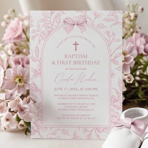 May include: A pink floral baptism and first birthday invitation card with text. The card features the name "Caroline Hudson" and event details. Two white baby shoes with pink bows are in the foreground. The card is surrounded by pink flowers.