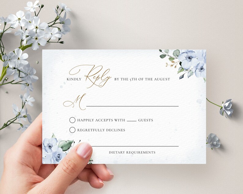 May include: A white RSVP card with blue watercolor flowers and gold calligraphy. The text reads "Kindly Reply by the 5th of August". There are two options for guests to choose from: "Happily Accepts with ___ guests" and "Regretfully Declines". There is also a space for dietary requirements.