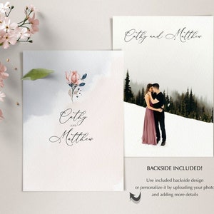 May include: A wedding invitation with a watercolor background and a floral design. The invitation says "Cathy and Matthew" in a script font. The back of the invitation has a photo of a couple in a snowy landscape.
