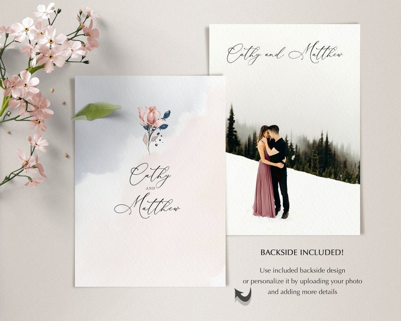 May include: A wedding invitation with a watercolor background and a floral design. The invitation says "Cathy and Matthew" in a script font. The back of the invitation has a photo of a couple in a snowy landscape.