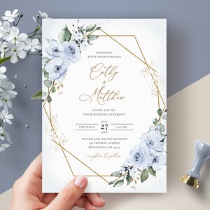 May include: Wedding invitation with a gold geometric frame and blue watercolor flowers. The invitation reads "Together with their families Cathy & Matthew Invite you to their wedding ceremony Saturday Aug 27 1:00 PM Woodland Grand Mansion 216 Thomas Avenue Pensacola, FL 32514 Reception to follow"