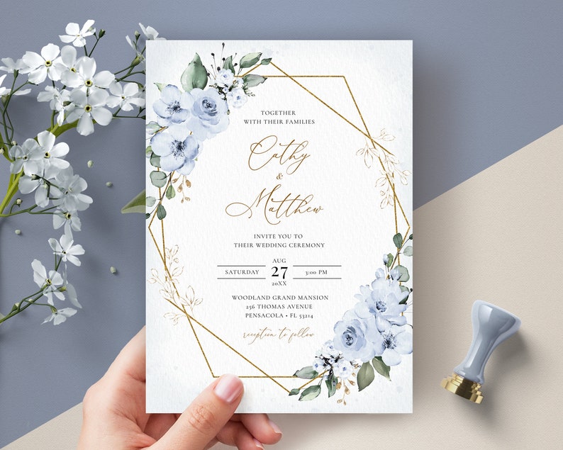 May include: Wedding invitation with a gold geometric frame and blue watercolor flowers. The invitation reads "Together with their families Cathy & Matthew Invite you to their wedding ceremony Saturday Aug 27 1:00 PM Woodland Grand Mansion 216 Thomas Avenue Pensacola, FL 32514 Reception to follow"