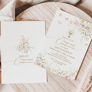 May include: Two First Holy Communion invitations. The invitations are cream-colored with floral and butterfly accents in pastel colors. The text reads "Amelia's First Holy Communion" and includes event details.