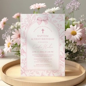 May include: A pink and white invitation card for a baptism and first birthday celebration. The card features floral illustrations and the text "Baptism & First Birthday" with event details. The card is displayed on a wooden tray with a floral arrangement.