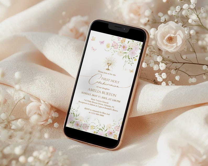 May include: A smartphone displays a First Holy Communion invitation. The invitation features floral and butterfly illustrations in soft pastel colors. The text includes the name Amelia Burton, the date, time, and location of the event.