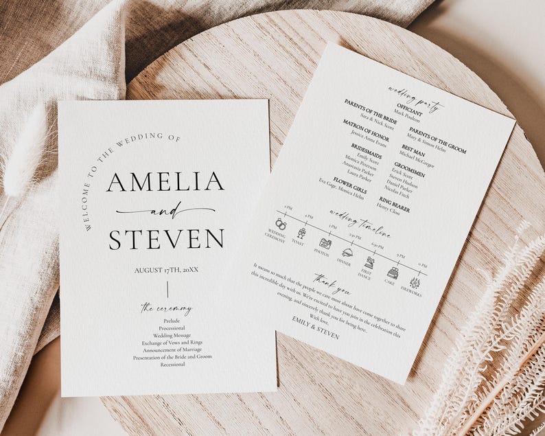 May include: Two wedding stationery cards with elegant typography. One card reads "Welcome to the Wedding of Amelia and Steven" with the date. The other card lists the wedding party and timeline. The cards are on a wooden surface.