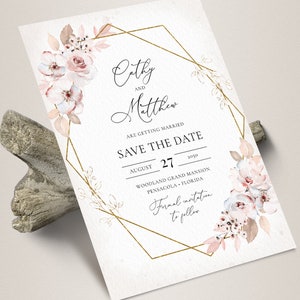 May include: A Save the Date card with floral watercolor accents. The card features the names "Cathy and Matthew" and the date August 27, 2050. A gold geometric frame surrounds the text and floral elements.