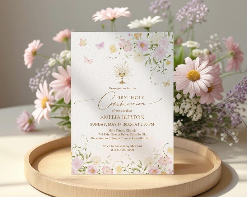 May include: A First Holy Communion invitation with floral and butterfly accents. The invitation features the text "First Holy Communion" and details for Amelia Burton's ceremony, including the date, time, and location. The invitation is on a wooden tray with flowers.
