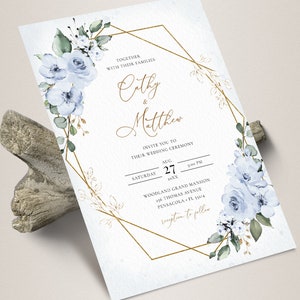 May include: A wedding invitation with a gold geometric frame and blue watercolor flowers. The invitation reads "Together with their families Cathy & Matthew Invite you to their wedding ceremony Saturday August 27 20XX Woodland Grand Mansion 256 Thomas Avenue Pensacola FL 32514 Reception to follow"