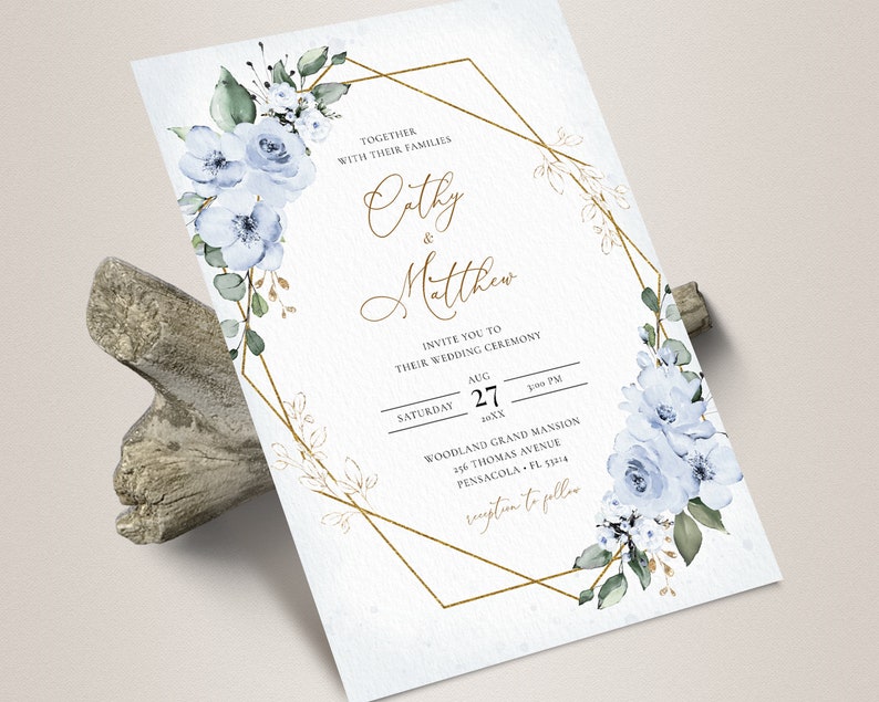 May include: A wedding invitation with a gold geometric frame and blue watercolor flowers. The invitation reads "Together with their families Cathy & Matthew Invite you to their wedding ceremony Saturday August 27 20XX Woodland Grand Mansion 256 Thomas Avenue Pensacola FL 32514 Reception to follow"