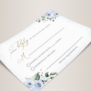 May include: A white RSVP card with blue floral accents. The card has a gold script font that says "Kindly Reply by the 5th of August". There are two radio buttons with the text "Happily Accepts with ___ guests" and "Regretfully Declines". The card also has a section for "Dietary Requirements".