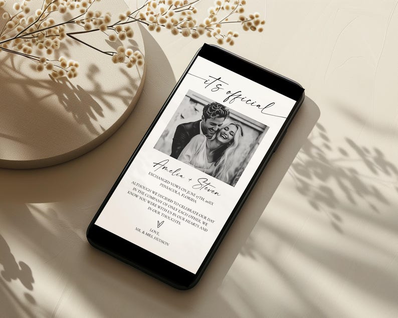 May include: A smartphone displays a wedding announcement with a black and white photo of a couple. The text reads "it's official" and includes the names Amelia and Steven, along with a message and the words "Love, Mr. & Mrs. Hudson."