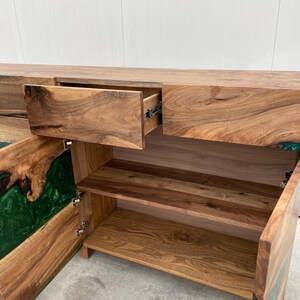 May include: A wooden cabinet with two drawers and two doors. The doors are open, revealing shelves and a green epoxy resin inlay. The cabinet is made of dark wood with a natural grain.