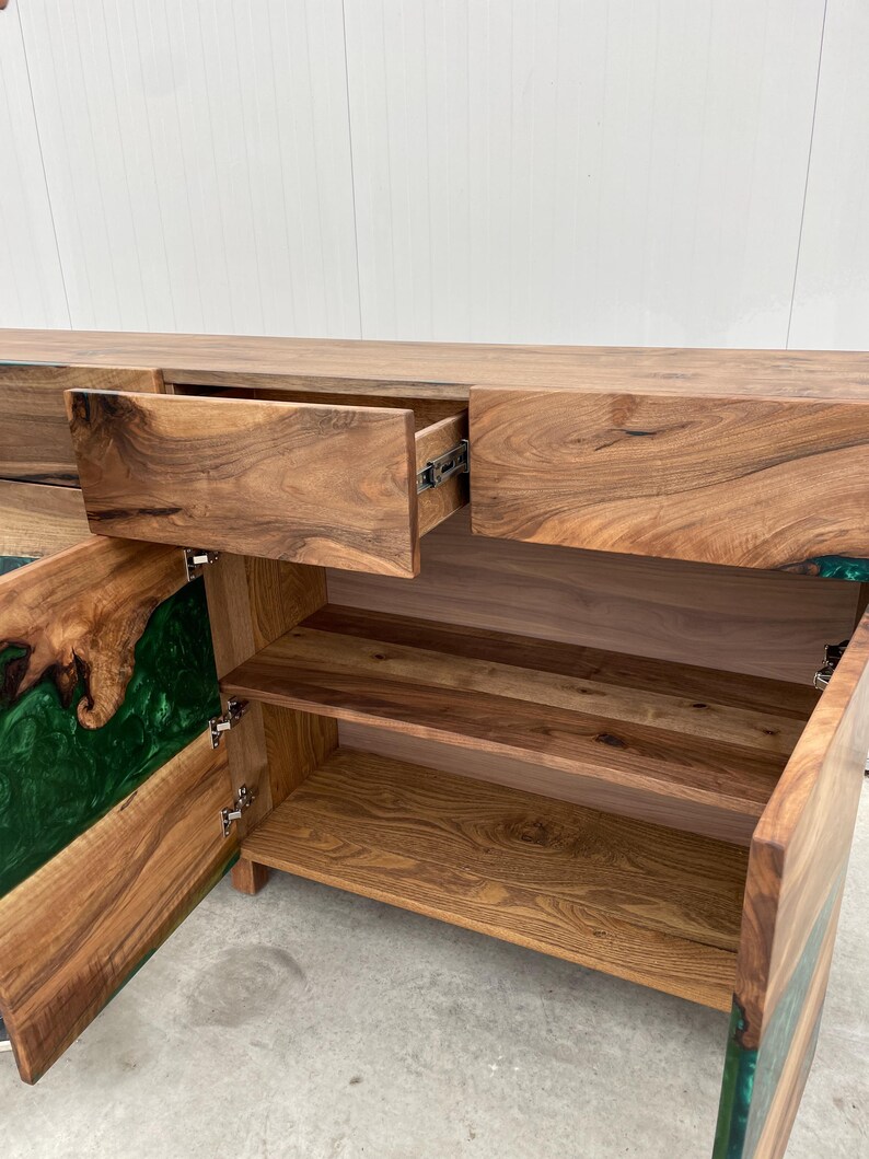 May include: A wooden cabinet with two drawers and two doors. The doors are open, revealing shelves and a green epoxy resin inlay. The cabinet is made of dark wood with a natural grain.