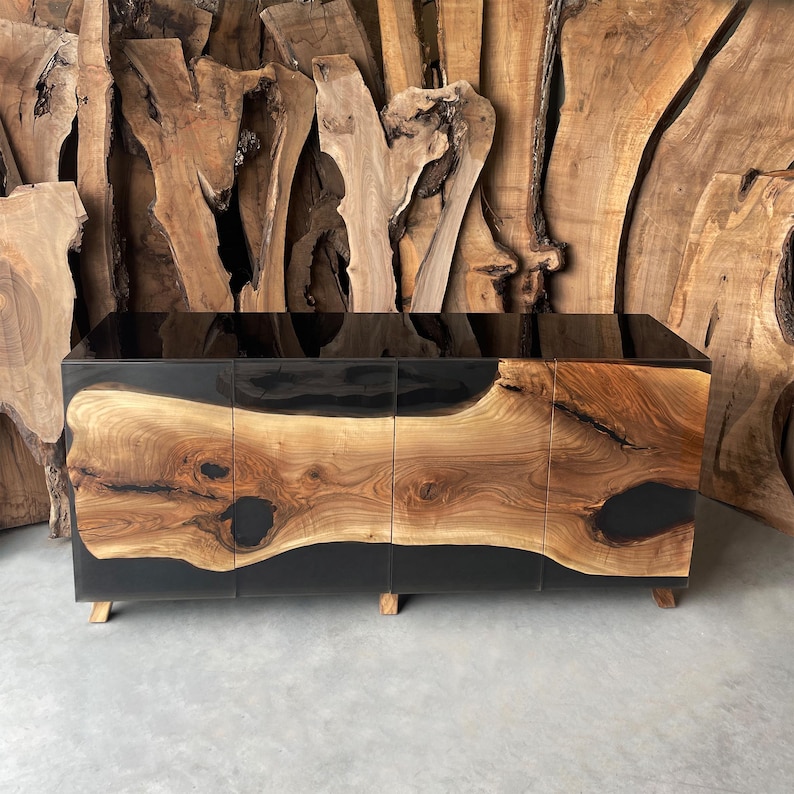 May include: A black and brown wooden cabinet with three doors and black epoxy resin accents. The cabinet has a modern design and is made of natural wood.