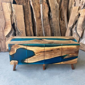 May include: A wooden cabinet with three drawers and a blue resin inlay. The cabinet has a modern design and is made of natural wood.