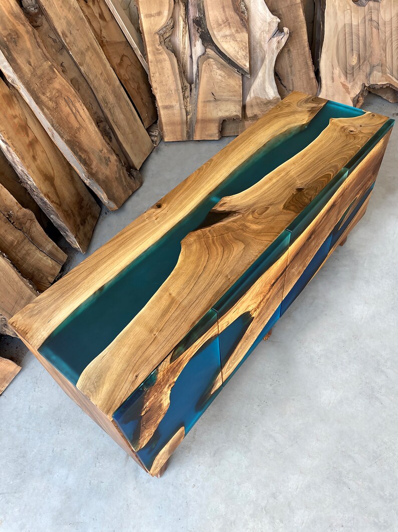 May include: A wooden console table with two drawers features a unique design with a blue resin river flowing through the wood grain.