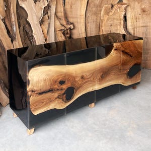 May include: A black and brown wooden cabinet with three doors. The cabinet is made of wood with a black epoxy resin finish. The doors are made of wood with a natural finish. The cabinet has a modern design and is perfect for a living room or dining room.
