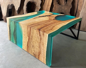 May include: A square coffee table with a wooden top and a teal blue epoxy resin inlay. The table has a black metal frame.