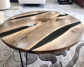 May include: Round wooden coffee table with black epoxy resin inlay. The table has a natural wood finish and black metal hairpin legs.