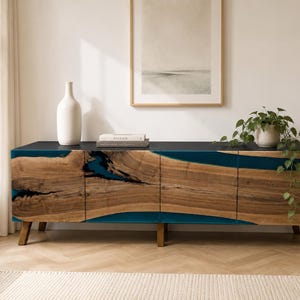 Puede incluir: Un aparador rectangular largo con cuatro puertas de armario hechas de losas de madera natural con bordes irregulares y una incrustación de resina azul turquesa. La pieza tiene una superficie superior negra y cuatro patas de madera inclinadas.