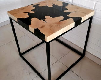 Op de afbeelding: Een vierkante bijzettafel met een blad van zwart epoxyhars en hout en een zwart metalen frame.