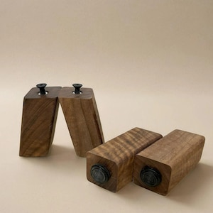 May include: Four wooden furniture legs with black rubber feet. The legs are made of dark wood with a natural grain pattern.