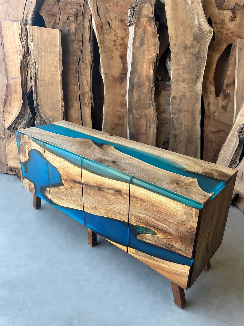 May include: A wooden cabinet with three drawers and a blue resin top. The cabinet has a modern design and is made of natural wood.