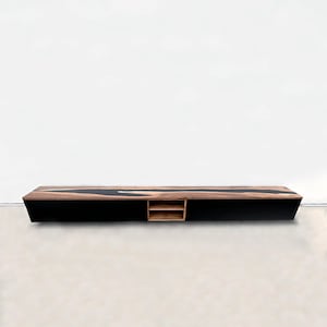 Puede incluir: Una consola multimedia negra y de madera con un estante en el centro. La parte superior de la consola tiene un diseño de río de epoxi negro.